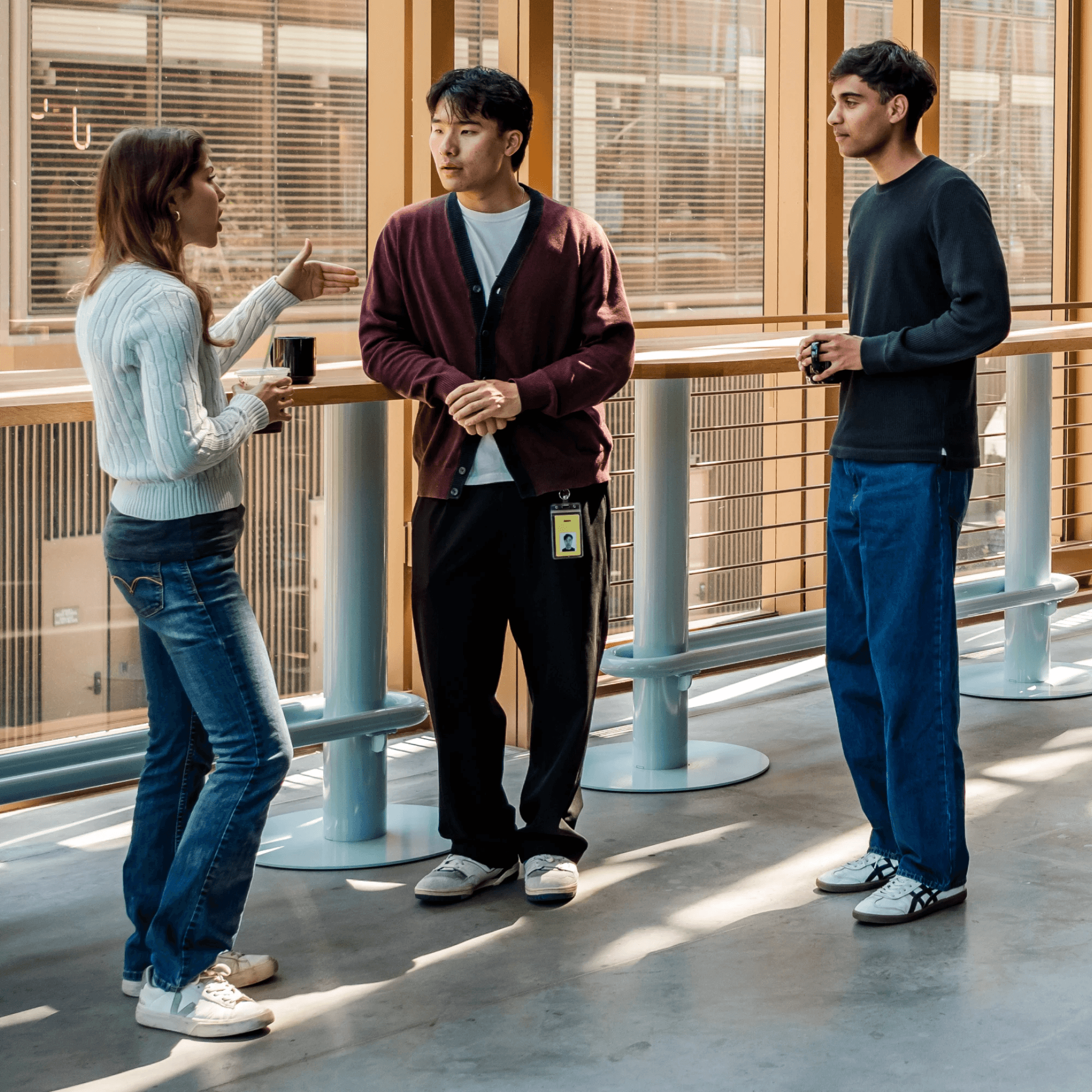 Three early-career colleagues talking together in a sunlit office